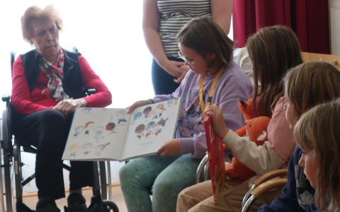 Mädchen liest Senioren Bilderbuch vor